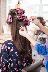 Hairdresser taking off curlers from woman long hair