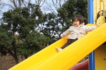 Fototapeta na wymiar 滑り台で遊ぶ赤ちゃん(1歳児)