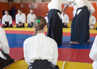 A girl in kimono and hakama sitting on tatami on martial arts seminar. Selective focus