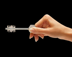 Woman's hand holding key to the apartment isolated on black background