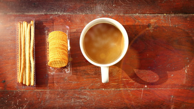 Coffee cup with smoke and cracker on wood. Light ray effect. UHD 4k 3840x2160.
