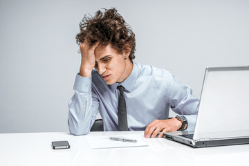 Entrepreneur dissatisfied with his earnings, profit, income, gain, benefit, margin. Modern businessman at the workplace working with computer, depression and crisis concept
