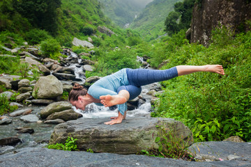 Woman doing yoga oudoors at tropical waterfall