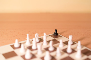 Chess pieces as metaphor - racism and bullying, one black piece is in the corner surrounded by big...