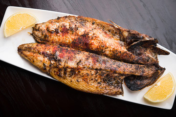 Fish on the grill with lemon on white plate