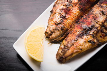 Fish on the grill with lemon on white plate