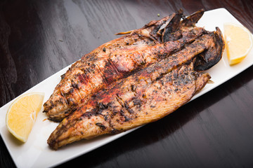 Fish on the grill with lemon on white plate
