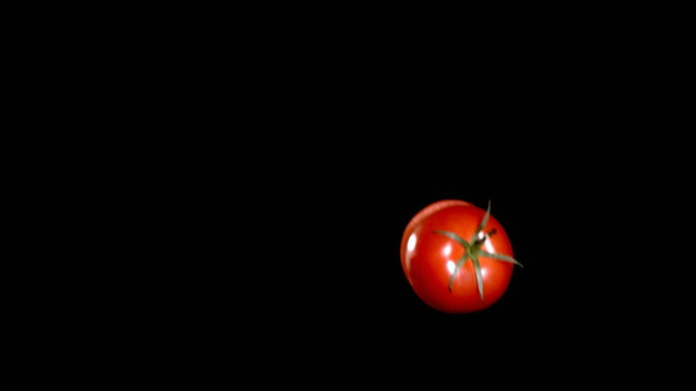 Knife slicing a tomato in mid-air, slow motion