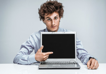 Young businessman indicates a screen laptop. Modern businessman at the workplace working with computer