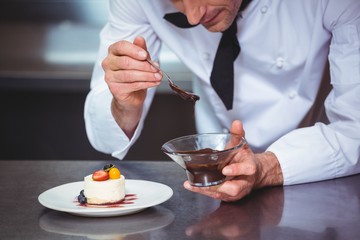 Obraz na płótnie Canvas Chef putting chocolate sauce on a dessert