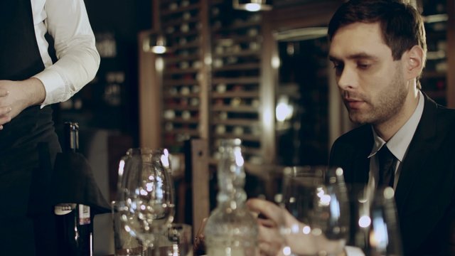 Sommelier pouring red wine into glass of restaurant guests