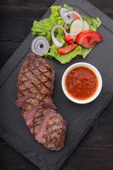 beef steak on with fresh salad on stone