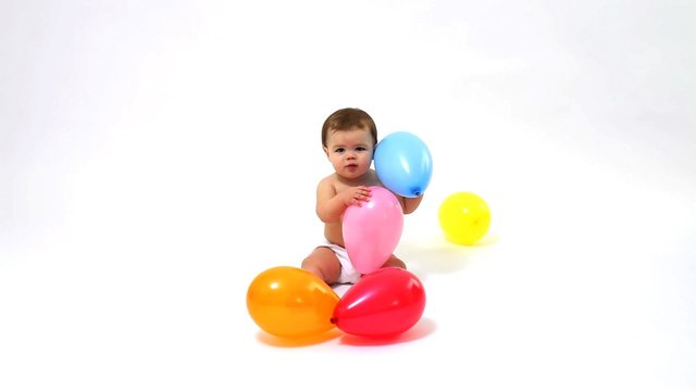 Baby playing with balloons on white background
