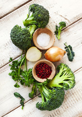 Fresh green broccoli, parsley, onion, salt and red pepper on woo
