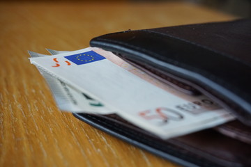 Detail of an EU flag displayed on the Euro (EUR, €) bank note inserted in the leather wallet