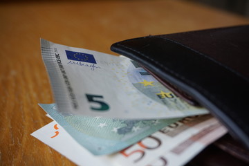 Detail of an EU flag displayed on the Euro (EUR, €) bank note inserted in the leather wallet