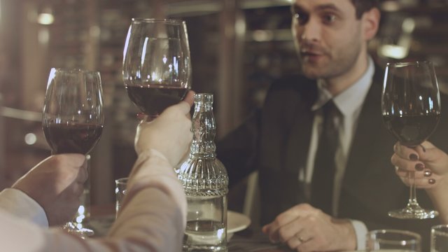 Friends clink glasses with red wine during a meeting in a restaurant