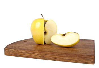 Yellow apple and slice on wooden cutting board on a white backgr