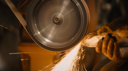 Craftsman uses a belt sander in machine shop.