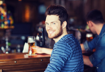 happy young man drinking beer at bar or pub