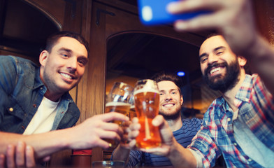 male friends with smartphone drinking beer at bar