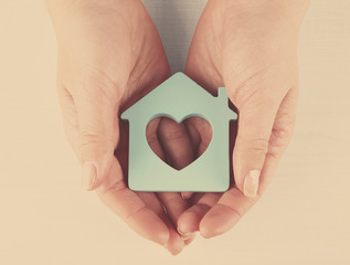 Female hands with model of house on wooden table background