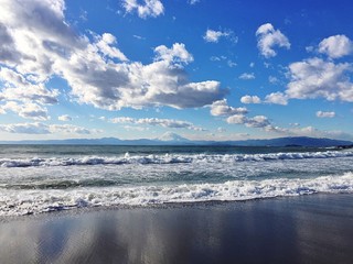 波打つ海岸から見た富士山と青空