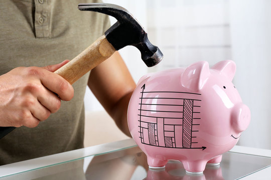 Man with a hammer going to break the piggy bank, close up