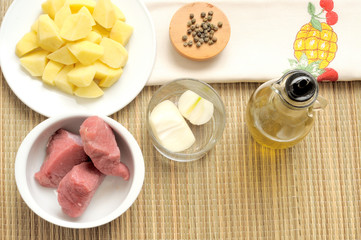 ingredienti per spezzatino o stufato. bocconcini di manzo, patata tagliate, cipolla, olio e.v.o. pepe. Vista dall'alto, luce naturale.