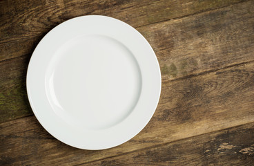 Empty white plate on rustic wooden background