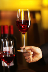 Male hand holding glasses of wine in the bar