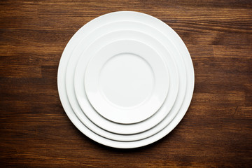 Empty white plates on rustic wooden background