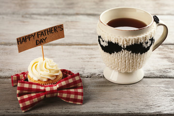 Happy fathers day special cupcake, cup of tea and bow tie on wooden table