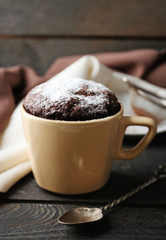 Chocolate fondant cake in cup on wooden table closeup