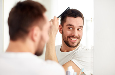 happy man brushing hair  with comb at bathroom