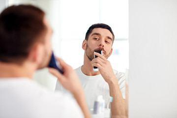 man shaving mustache with trimmer at bathroom