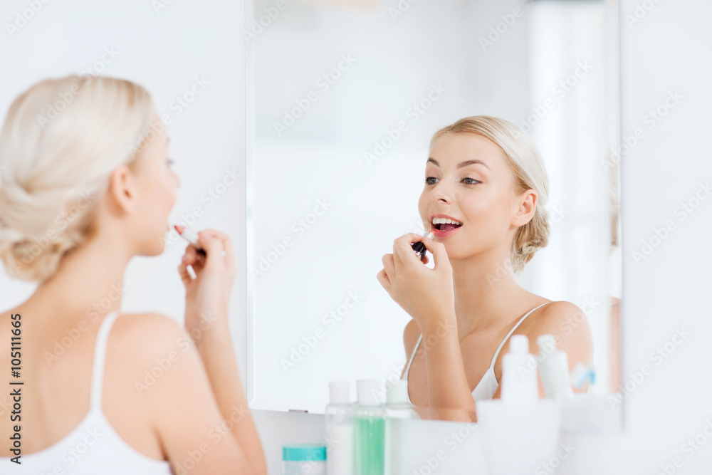 Wall mural woman with lipstick applying make up at bathroom