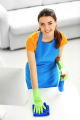 Young woman cleaning workplace with computer monitor in the office