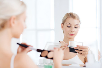 woman with makeup brush and foundation at bathroom