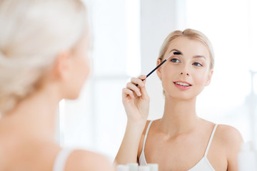 woman brushing eyebrow with brush at bathroom