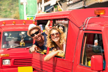 Cheerful tourist couple in tuk tuk thai taxi with pointing finger - Smiling friends having fun on road trip in Phuket island - Joyful people travel around the world - Focus on the woman face