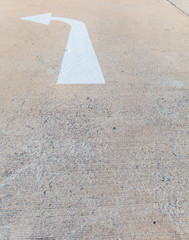 Close-up of cement street floor with white painted arrow sign