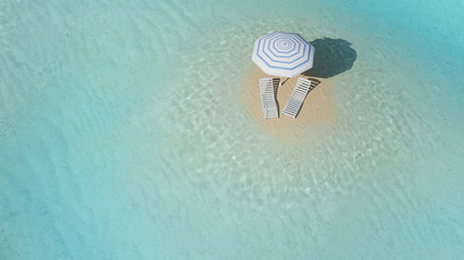Fototapeta na wymiar Island with umbrella surrounded by crystal clear water