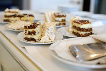 The cut pieces of cake on plates on white tablecloths. Celebration and holiday. Sweet dish for the guests in the restaurant. Festive table with about a sweet dessert.