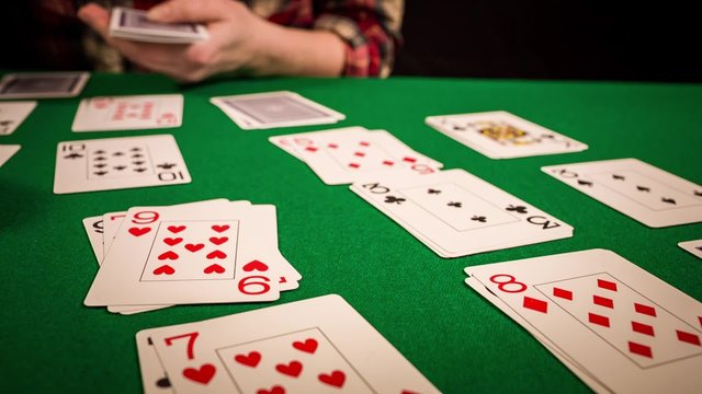 Close up of female hands holding cards and playing solitaire