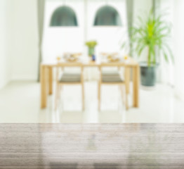 granite table top and blur of wooden dining table and chairs with elegant table setting