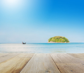 wooden table top with blur of beautiful seascape with blue sea beach island and the long tail boat under clear sky in summer,kata beach - phuket