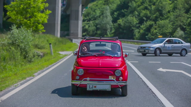 Red vintage car is coming from a side road to the main road