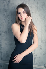 beautiful girl posing in a black evening dress. toned portrait in the studio