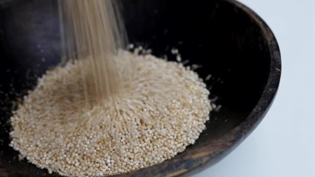 puffed Amaranth seeds pouring into rustic bowl close-up Isolated video